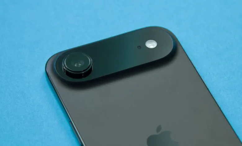 Close-up of a dark smartphone camera module with a prominent lens and flash on a blue background.