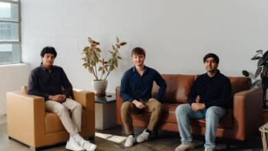 Three young men sitting in a modern office lounge area.