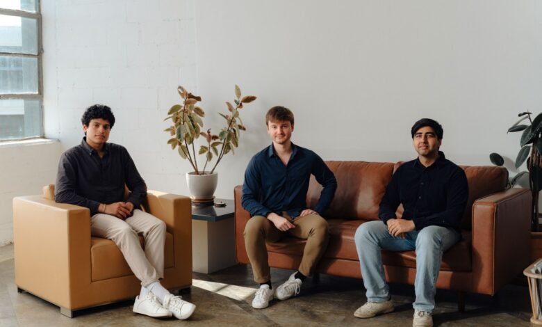 Three young men sitting in a modern office lounge area.