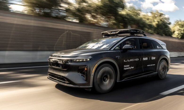 A black Lucid electric SUV with Nuro and Uber branding drives on a highway.