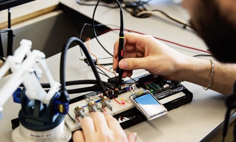 Close-up of hands working on an electronic circuit board with a probe and small screen.