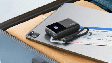 Compact black power bank with digital display on a tablet, next to a plane ticket.
