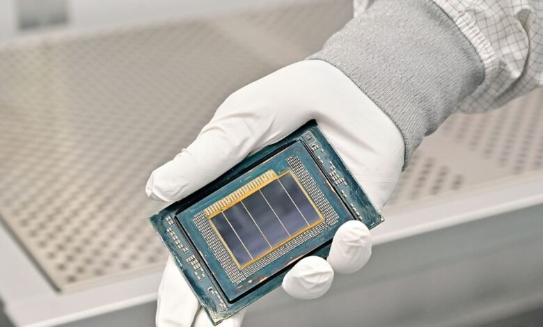 Close-up of a hand in a white glove holding a complex computer processor chip.