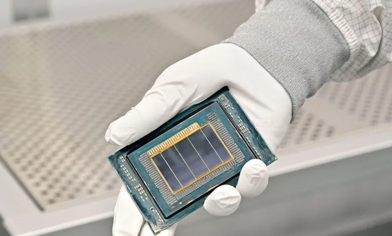 Close-up of a hand in a white glove holding a complex computer processor chip.
