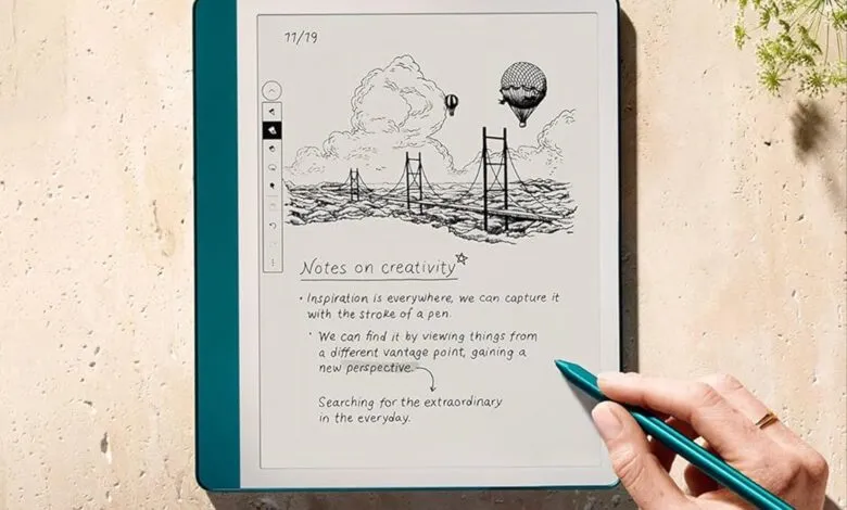 Hand holding a stylus to write notes on a Kindle Scribe e-reader.