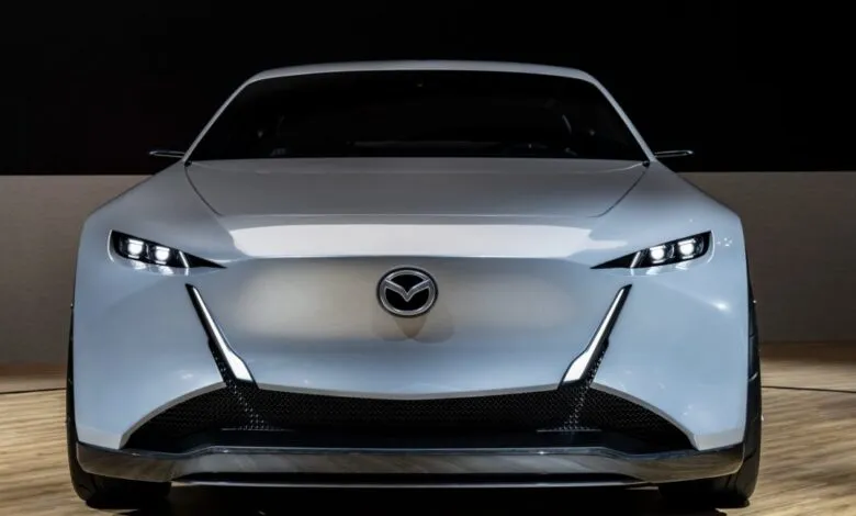 Front view of a sleek, white Mazda concept car with sharp LED headlights and a distinctive grille.