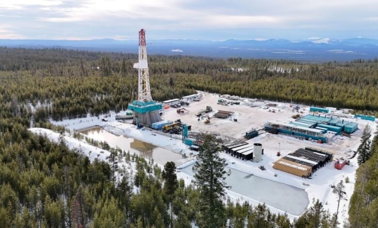 Aerial view of a winter oil drilling site surrounded by snow-covered pine forest.