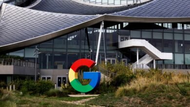 Large, colorful Google 'G' logo in front of a modern building with a distinctive curved roof.