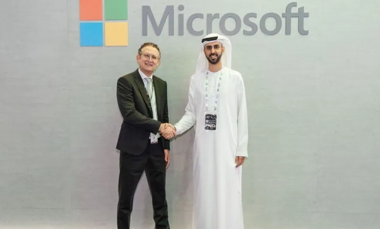 Two men shaking hands in front of a Microsoft logo.