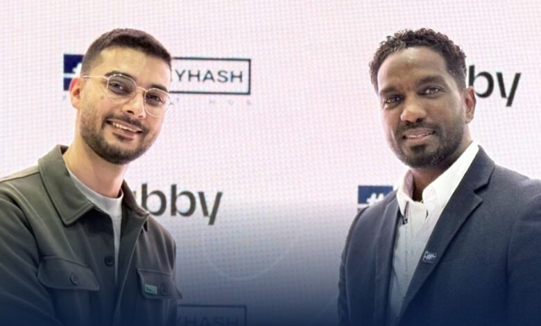 Two men smiling in front of a backdrop with logos for MoneyHash and Tabby.