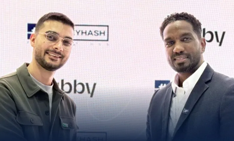 Two men smiling in front of a backdrop with logos for MoneyHash and Tabby.