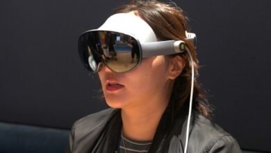 Woman wearing a white and gray virtual reality headset with reflective lenses.