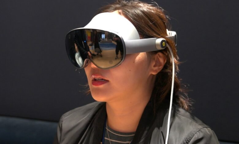 Woman wearing a white and gray virtual reality headset with reflective lenses.