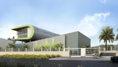 Modern architectural building with a curved green roof and glass facade.