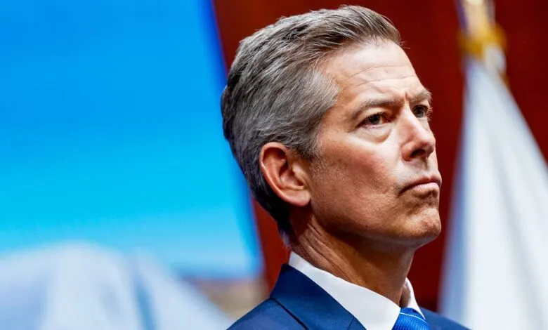 Close-up of a man with graying hair wearing a suit and blue tie, looking intently to the side.