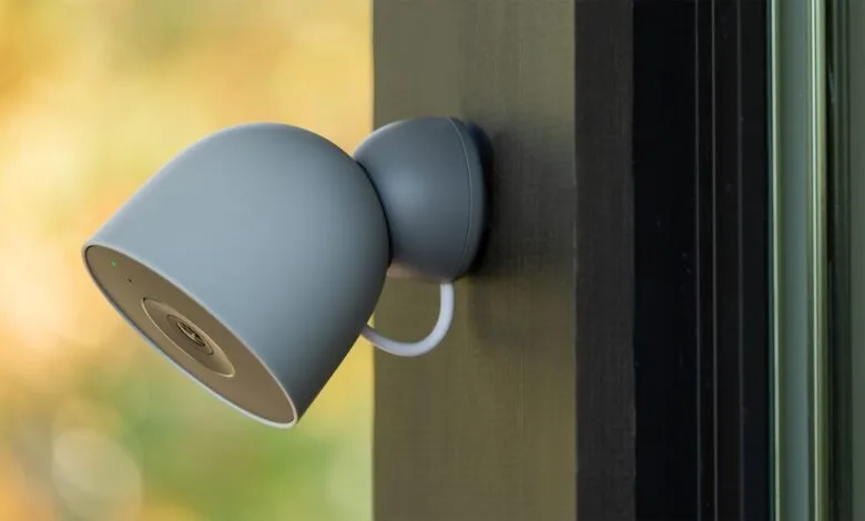 Close-up of a gray outdoor security camera mounted on a dark frame.