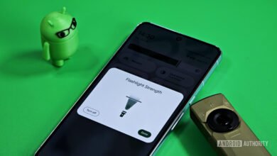 Smartphone displaying Android flashlight strength control UI with an Android mascot and a small flashlight.