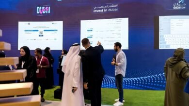 People at a digital technology exhibition looking at screens displaying information about investing in Dubai.