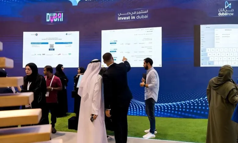 People at a digital technology exhibition looking at screens displaying information about investing in Dubai.