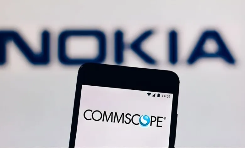 Smartphone displaying the CommScope logo in front of a blurred Nokia logo.