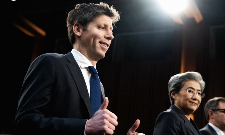Man in suit giving thumbs up, with two people behind him.