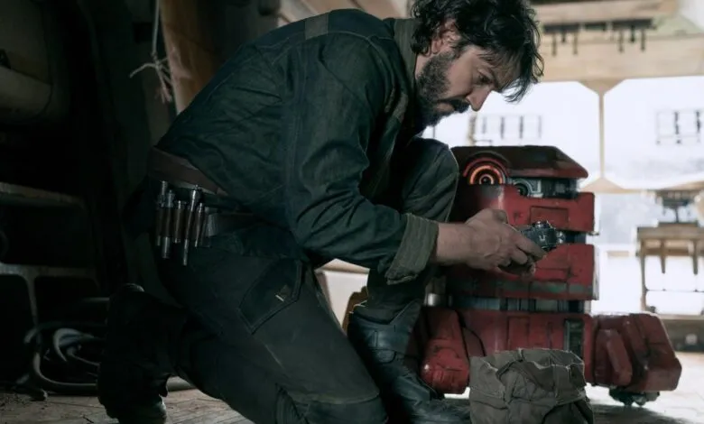 Diego Luna as Cassian Andor works on a droid in a dimly lit workshop.
