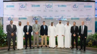 Group of men in suits and traditional attire posing in front of a large screen displaying the 'du' logo and 'WELCOME' text.