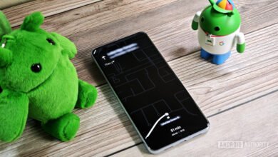 Smartphone displaying Google Maps navigation with a plush green character and Android figurine nearby.