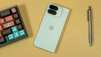 A light green Google Pixel phone with a dual-camera system next to a custom mechanical keyboard and a silver pen.