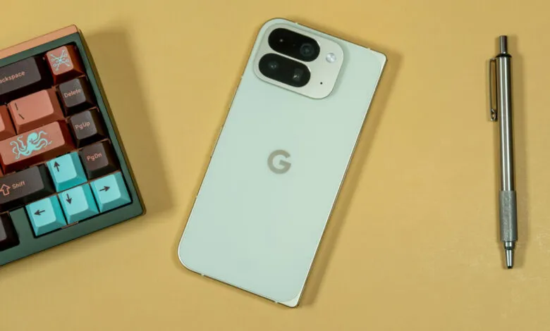 A light green Google Pixel phone with a dual-camera system next to a custom mechanical keyboard and a silver pen.