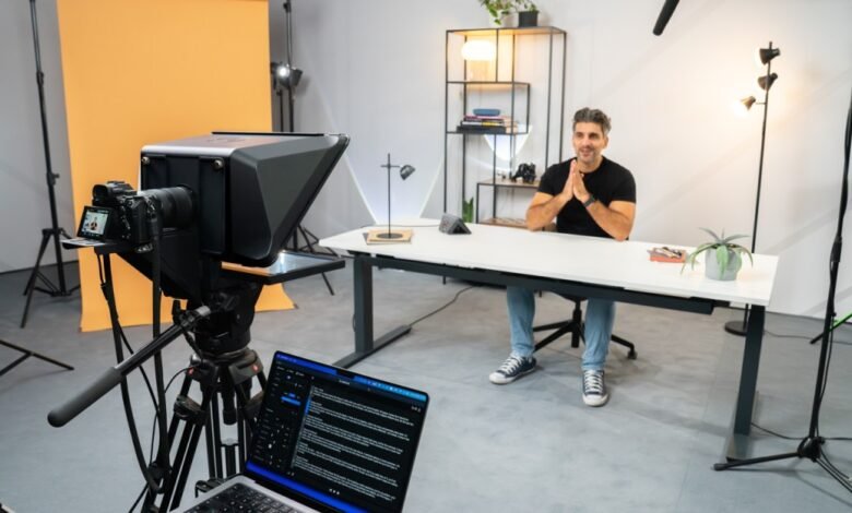 Man in a studio setting with a teleprompter, camera, and lighting for video production.