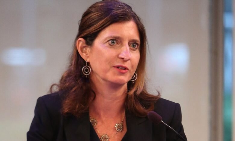 Close-up of Rebecca Blumenstein speaking into a microphone, wearing a black blazer and jewelry.