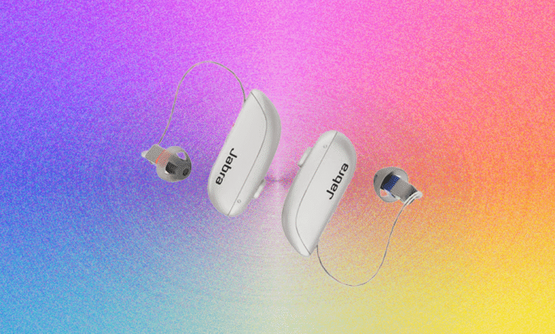Two white Jabra Enhance Select 700 hearing aids with clear wires and ear tips, set against a vibrant gradient background.