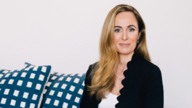 Professional portrait of a woman with blonde hair wearing a black blazer and white top.