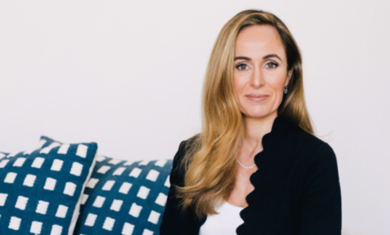 Professional portrait of a woman with blonde hair wearing a black blazer and white top.