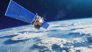 A satellite with solar panels orbits Earth, showing clouds and atmosphere.