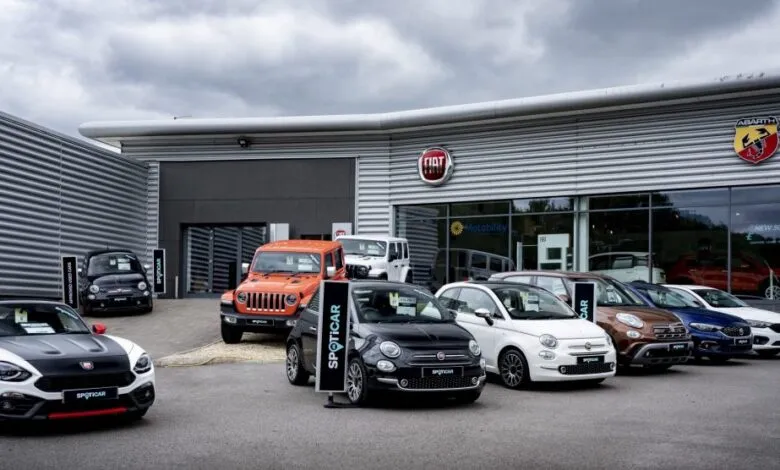 A row of Fiat and Abarth cars parked outside a modern dealership.