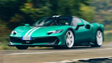 A green Ferrari 296 GTB with white racing stripes drives on a road.
