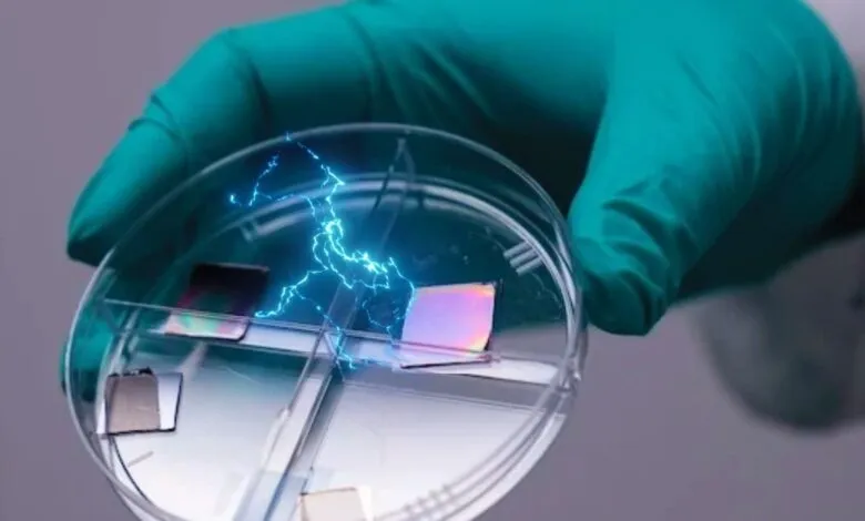 Gloved hand holding petri dish with iridescent squares and blue electrical sparks.