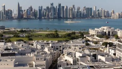 Panoramic view of Doha's modern skyline and waterfront, with white buildings in the foreground.