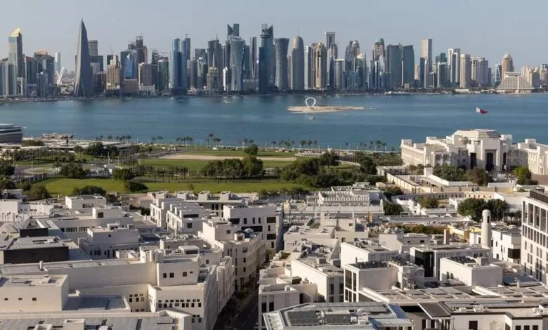 Panoramic view of Doha's modern skyline and waterfront, with white buildings in the foreground.