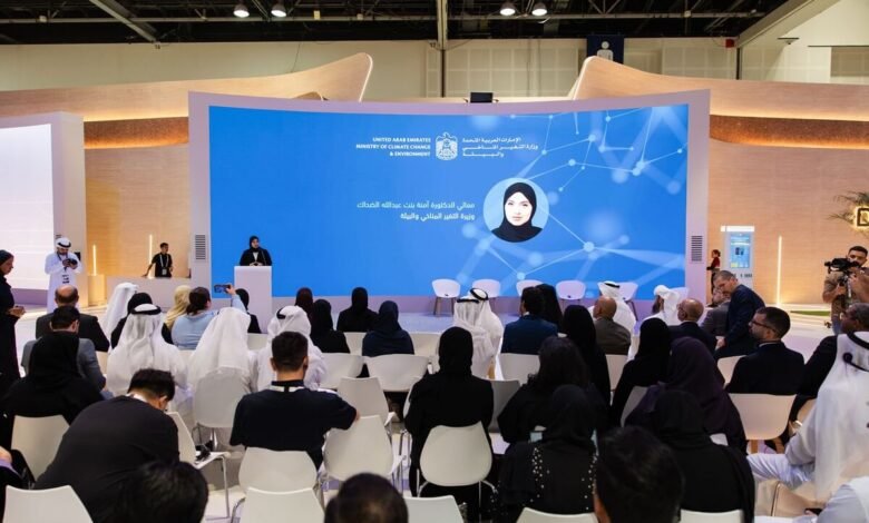 Speaker at podium addressing an audience in front of a large screen displaying the UAE Ministry of Climate Change and Environment logo.