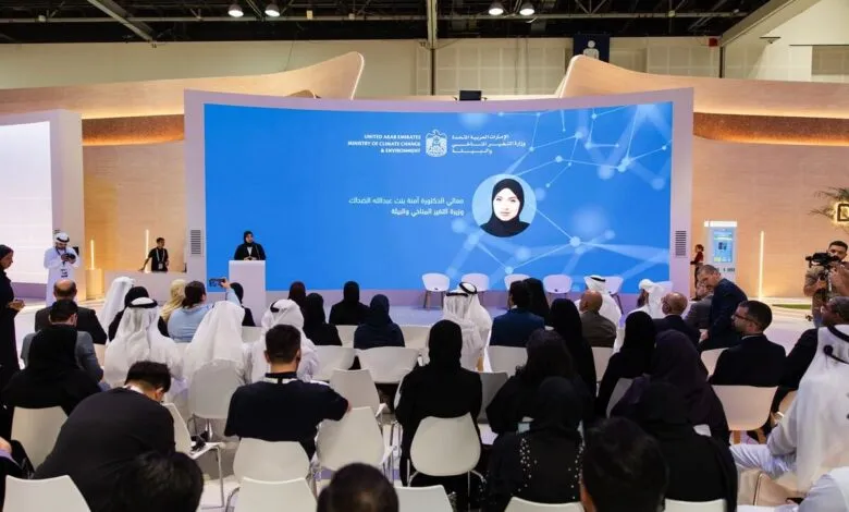 Speaker at podium addressing an audience in front of a large screen displaying the UAE Ministry of Climate Change and Environment logo.