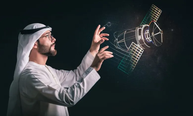 Man in traditional Emirati clothing interacting with a holographic satellite projection.