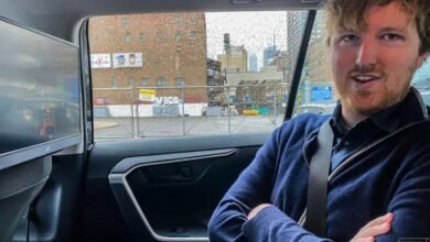 Man in car with screen showing city view, rainy day outside