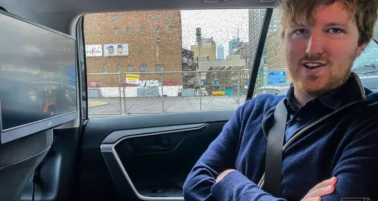 Man in car with screen showing city view, rainy day outside