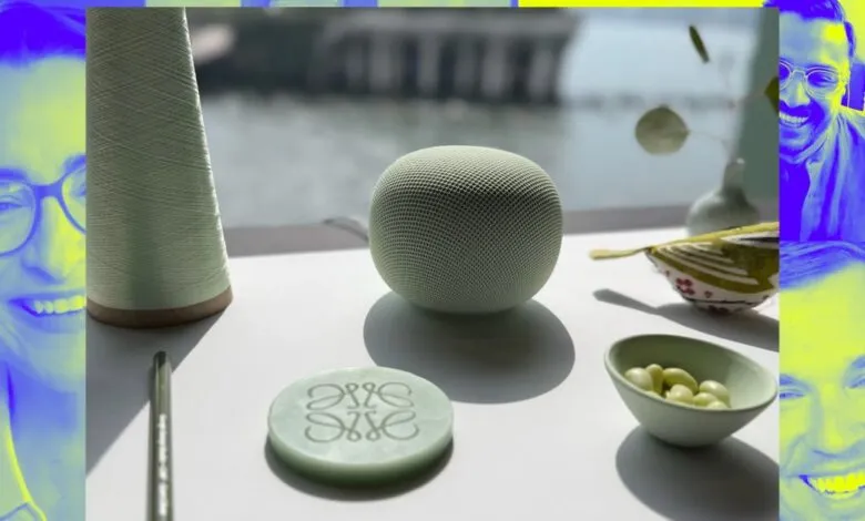 A light green smart speaker sits on a white surface next to a spool of thread and a decorative item.
