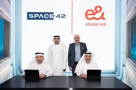 Four men in formal attire pose for a photo in front of logos for Space42 and Etisalat.