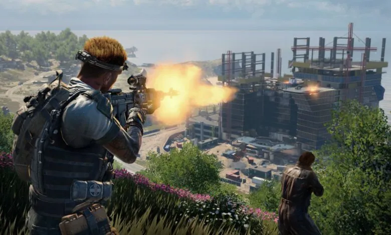 A soldier fires an assault rifle with muzzle flash, overlooking a construction site and the ocean.