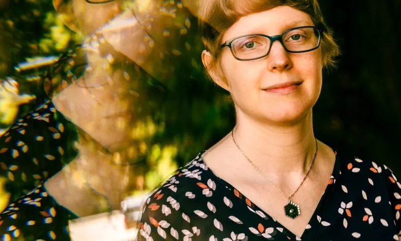Portrait of a woman with glasses and a floral dress, with a refracted background.